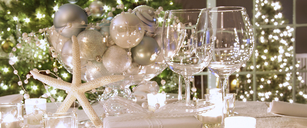 Elegantly lit holiday dinner table with white ribboned gift