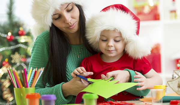 Handmade Christmas Cards - Mother and child cutting some colour paper both of them wearing a santa claus hat