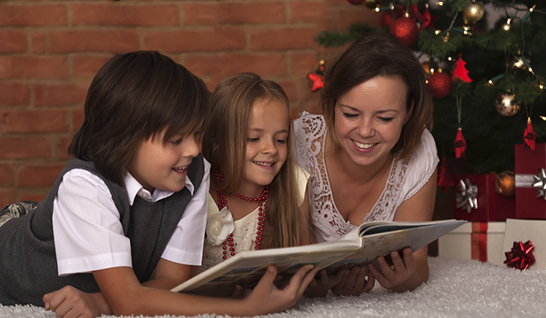 Winning Traditions - Two children listening to a Christmas Story book read by their mother