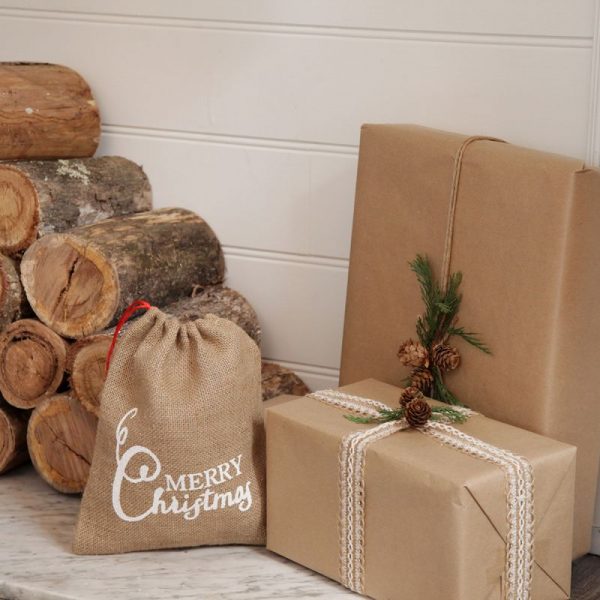 Jute Sack with printed Design merry Christmas Beside some wooden Logs
