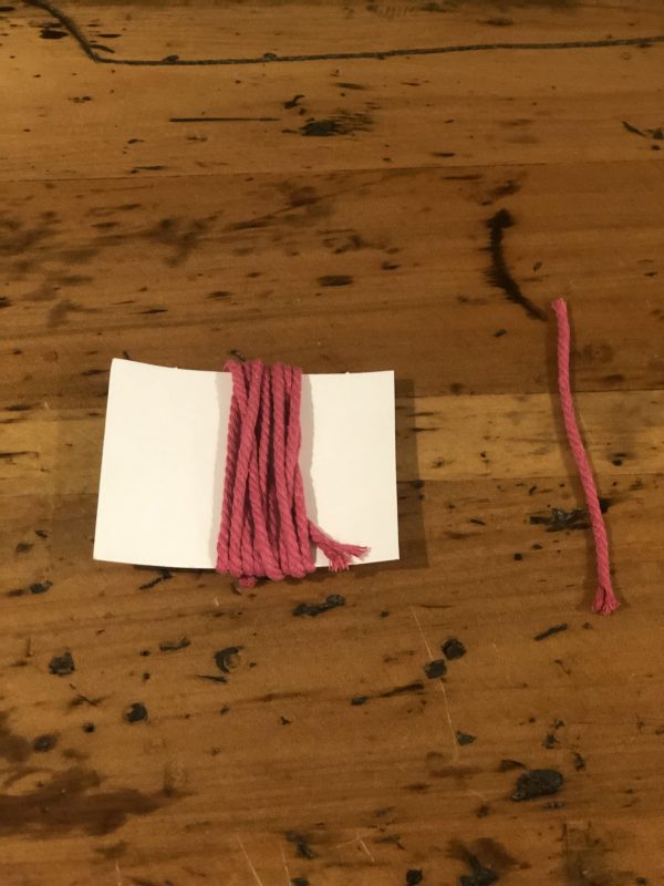 One Pink Tassles Placed in a wooden table wrapped in a piece of paper