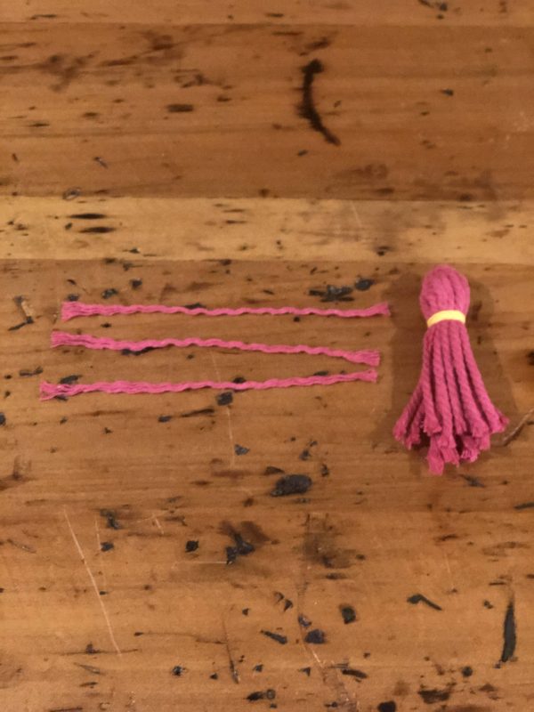One Pink Tassles Placed in a wooden table with an extra 3 strand of tassles