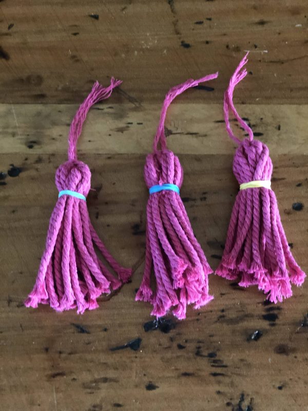 Three Purple Tassles Placed in a wooden Table