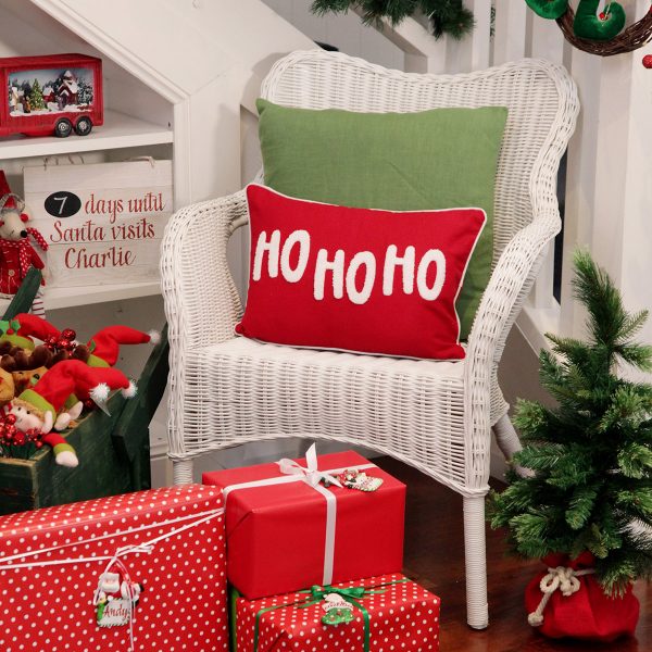 Ho Ho Ho Cushion Placed in a Rattan Chair with Christmas Presents
