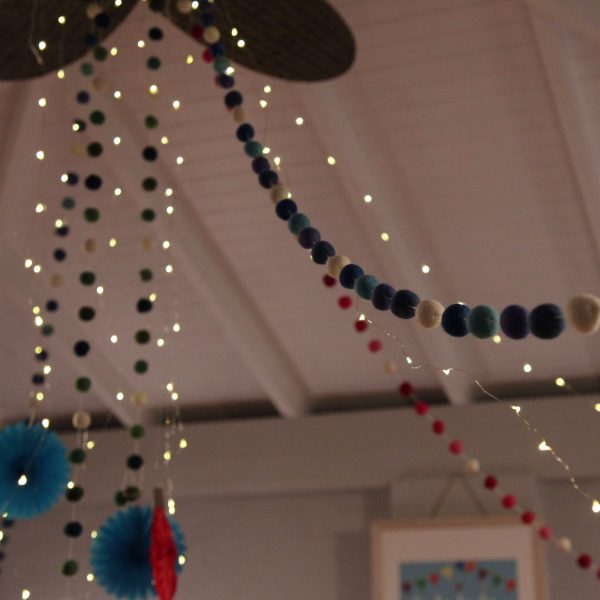 Falalala Llama Christmas Fiesta Blue Felt Ball Garland String lights hanged in the living room