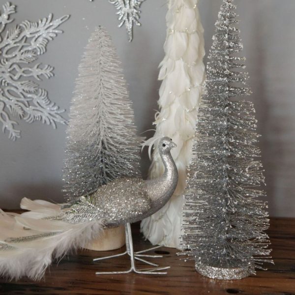 Silver frost Christmas Silver and White jewelled feather peacock and bottle bush tree behind is a snowflake hanging decor