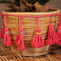 Falalala Llama Christmas Fiesta Tree Basket Craft Tassels placed in a rattan table Tassels in pink