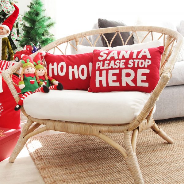 Candy Cane Christmas Santa Please Stop Here and Ho Ho Ho Cushion Cover placed on a rattan chair with 2 elves beside