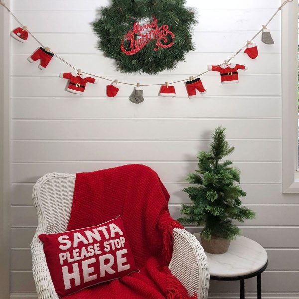 Santa Please Stop Here Cushion placed in a rattan Chair