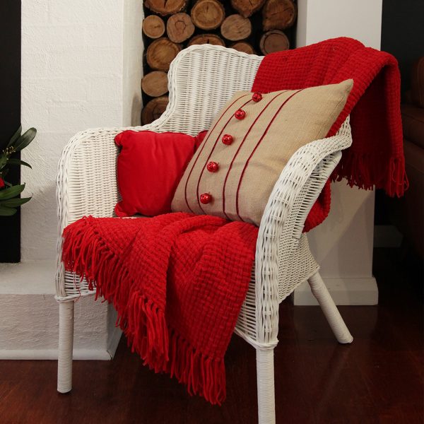 burlap cushion with red bells placed in a rattan chair