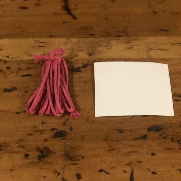Pink Tassel placed in a Wooden table with Plain White Card
