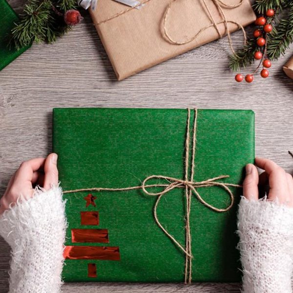 A hand holding a Wrapped christmas gift green with brown Tie
