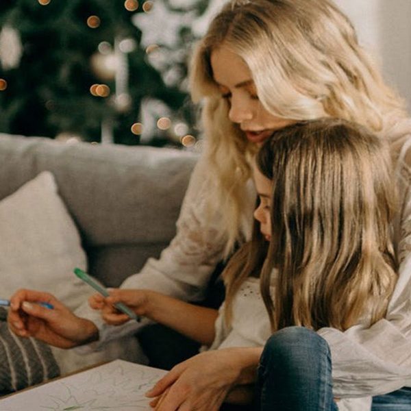 Mother teacher her daughter to draw while sitting in their living room Chair