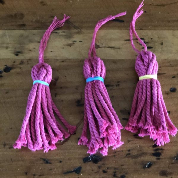 Three Purple Tassle Placed in a Wooden Table
