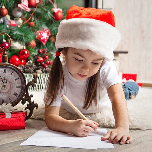 Little Girl Holding a Pencil and trying to draw while wearing a santa hat