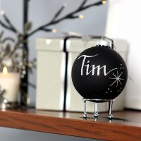 Personalised Black Bauble Named Tim Infront of a Christmas Gift
