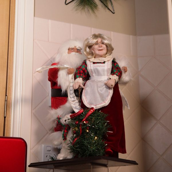 A Christmas Kitchen Between Windows and Hutch Mrs Claus Ornament and Mr Claus Ornament placed in the corner of the house
