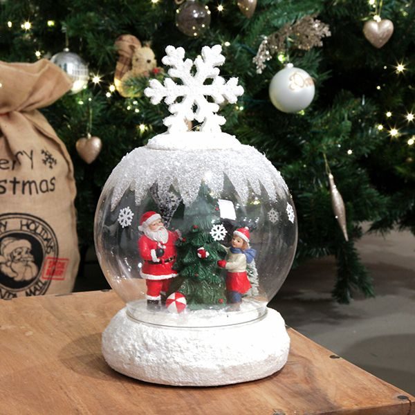 Light Up musical Santa Snowglobe with a snowflake design on top in front of a Christmas Tree