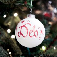 Personalised White Bauble Glass Named Deh hanging in a Christmas Tree