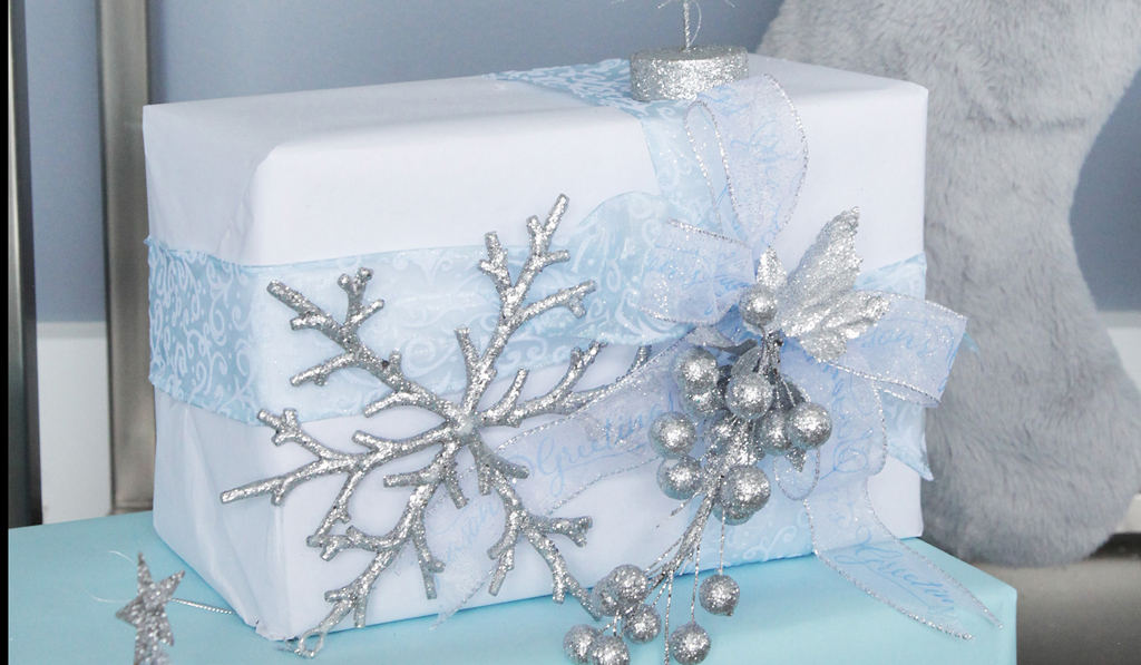 Gift boxed, wrapped in blue ribbon with Silver Glitter Berry Christmas Garland on top grey with grey pillow behind