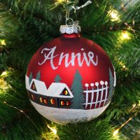 personalised red handpainted glass bauble hanging on tree name in silver glitter cottages tree and snow painted