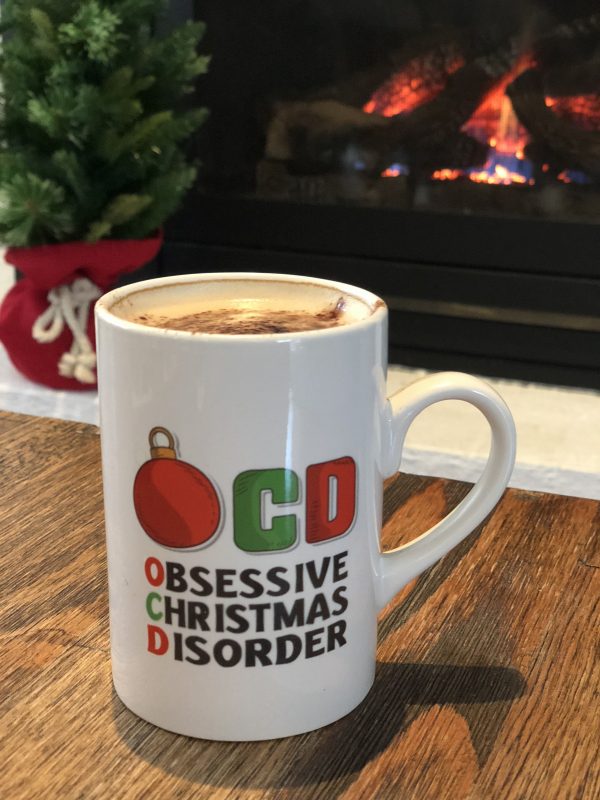 Obsessive Christmas Disorder Mug placed in front of the fireplace