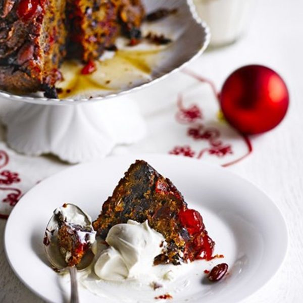 Chrismtas Pudding placed in a white plate with creamy icing red bauble also placed in the mantle