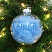 Blue feather clear glass personalised chrismtas bauble hanging in a christmas tree