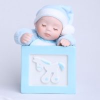 Baby in blue sitting closing hes eyes with a pony box
