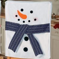 Snowman Chair cover with a blue scarf placed in the kitchen
