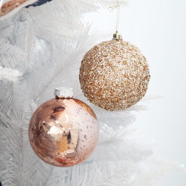 Rose gold sequin and mercury christmas baubles hanging in a white christmas tree