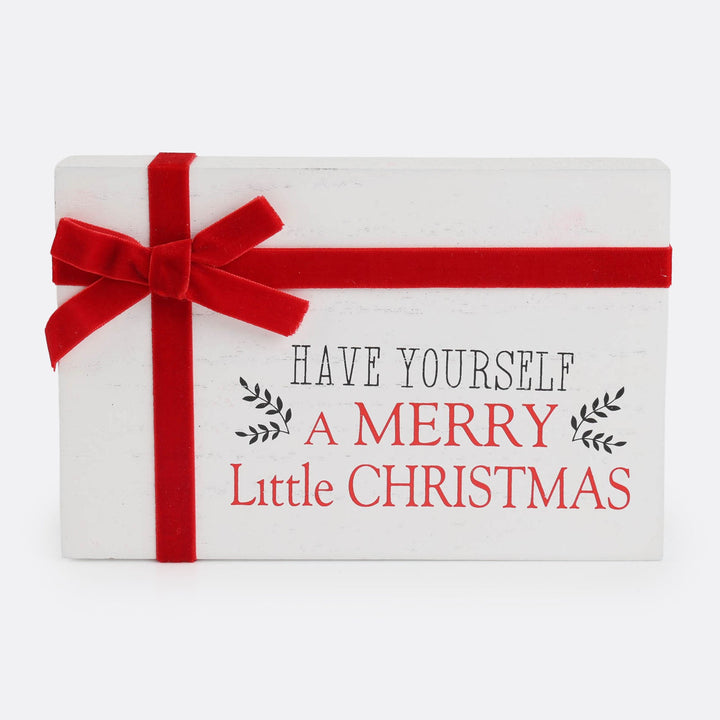 A rectangular white decorative sign with a red ribbon bow and red horizontal ribbon, printed with the phrase &